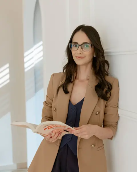 Naiara Nunes, psicóloga, em pé, segurando um livro aberto